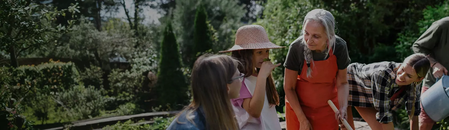 Personas haciendo jardinería juntas en un lujoso jardín de comunidad.