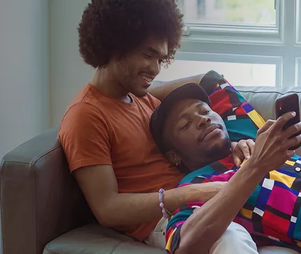 Pareja relajándose en un sillón mirando un teléfono
