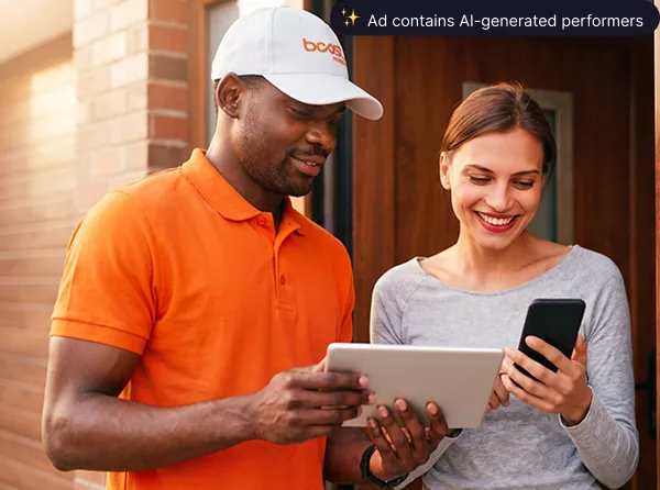 A Boost Mobile delivery driver helping a smiling customer set up a new smartphone at her door.