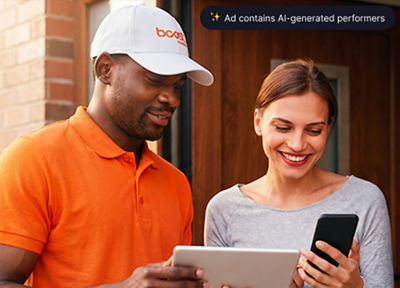A Boost Mobile delivery driver helping a smiling customer set up a new smartphone at her door.