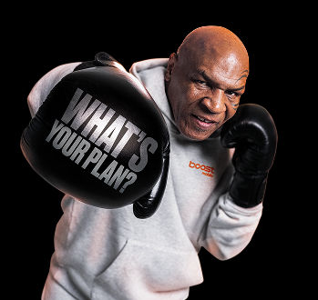 Mike Tyson, con una sudadera gris con capucha, lanzando un puñetazo hacia la cámara, con las palabras "¿CUÁL ES TU PLAN?" escritas en plata en su guante de boxeo negro.