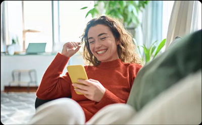 Mujer sonriendo mientras mira su teléfono