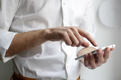 A person in a white shirt typing on a smartphone.