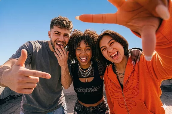 Tres amigos sonrientes posan juntos en una foto al aire libre.